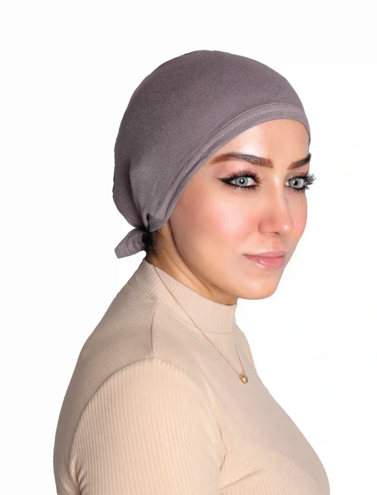 A woman models a Chic Grey Turban Cap for Women, viewed from the side with a slight smile, showcasing the comfortable fit and subtle textured fabric.