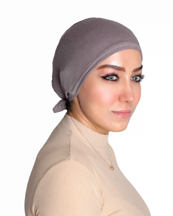 A woman models a Chic Grey Turban Cap for Women, viewed from the side with a slight smile, showcasing the comfortable fit and subtle textured fabric.
