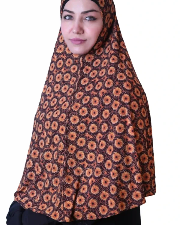 A woman models a Black & Orange Sunburst Rayon Hijab, viewed from the side, highlighting the intricate pattern and the flowing material of the garment.