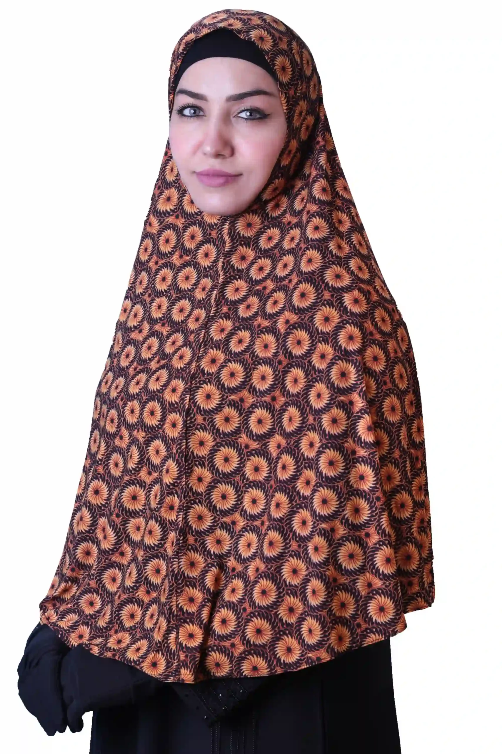 A woman models a Black & Orange Sunburst Rayon Hijab, viewed from the side, highlighting the intricate pattern and the flowing material of the garment.