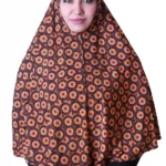 A woman models a stylish Black & Orange Sunburst Rayon Hijab, showing off the unique sunburst pattern and how the hijab drapes elegantly over her shoulder.