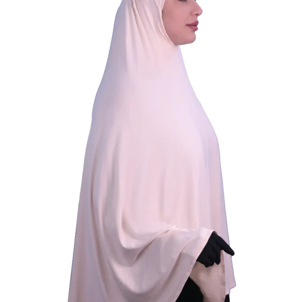 A woman modeling a luxurious fawn beige cotton hijab, smiling directly at the camera, showcasing the complete look of the garment.