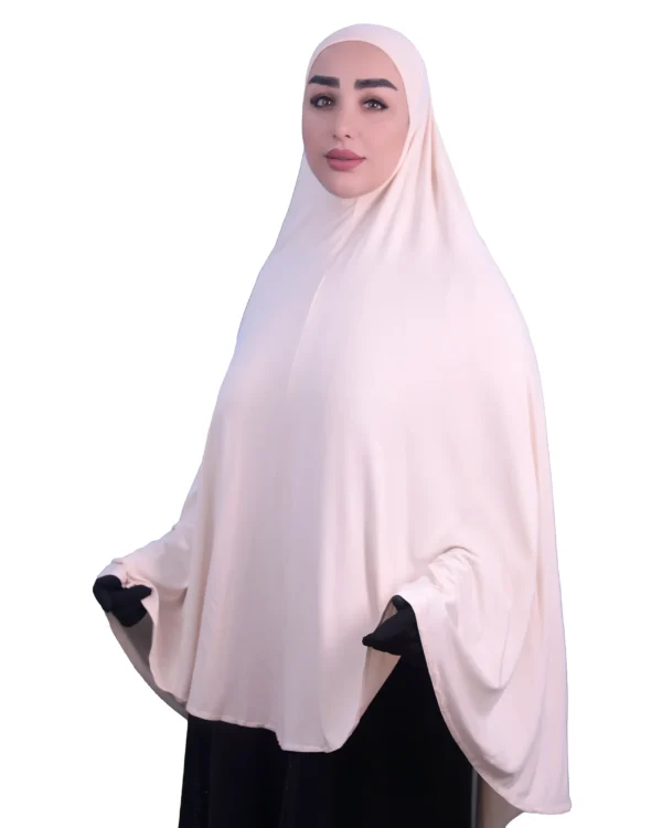 A woman modeling a luxurious fawn beige cotton hijab, looking directly at the camera with her hands slightly out, highlighting the full coverage and comfortable fit.