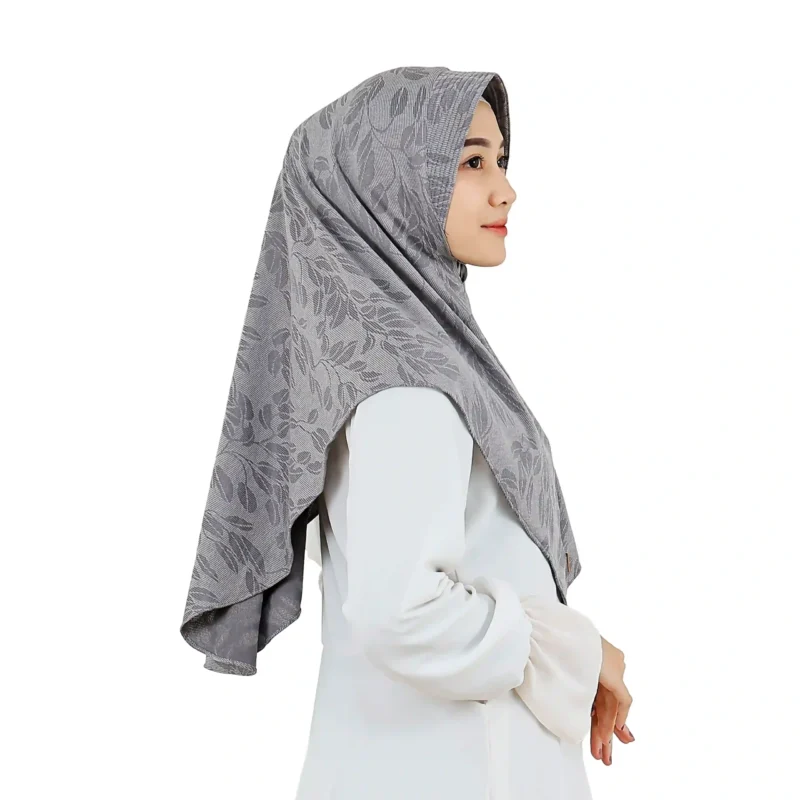 A woman models a Chic Grey Hijab with Leaf Pattern, viewed from the side, showcasing the comfortable fit around the face and the texture of the leaf-patterned fabric.