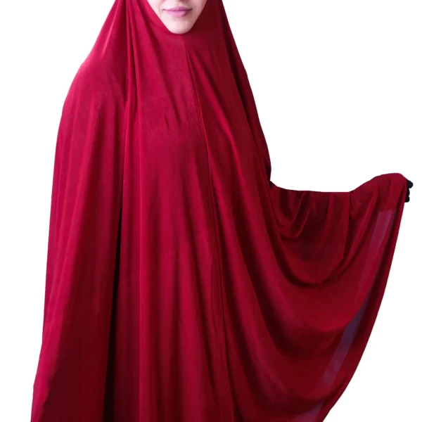 A woman models a stylish Red Satin Hijab for Women, standing at an angle while holding up the side of the flowing fabric to emphasize the material and volume.