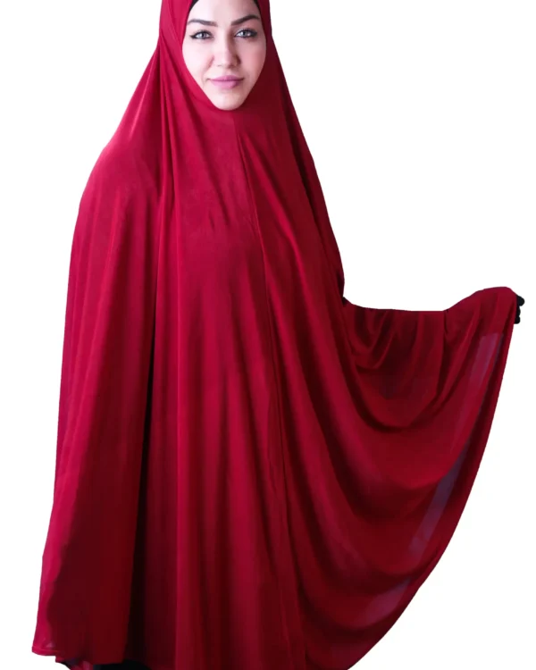 A woman models a stylish Red Satin Hijab for Women, standing at an angle while holding up the side of the flowing fabric to emphasize the material and volume.